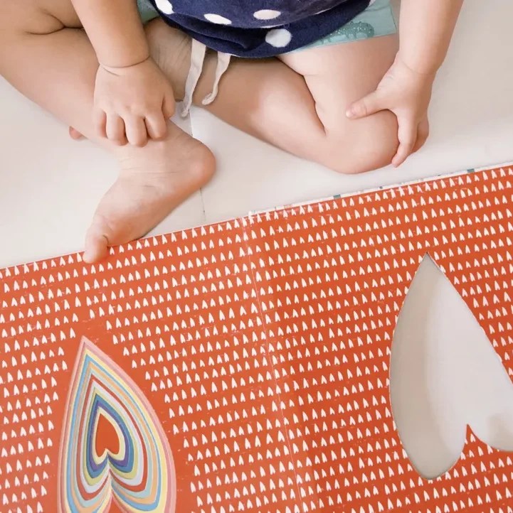 孩子閱讀繪本《Hello, Every Body!》,專注翻閱愛心圖案頁面,親子共讀日常。