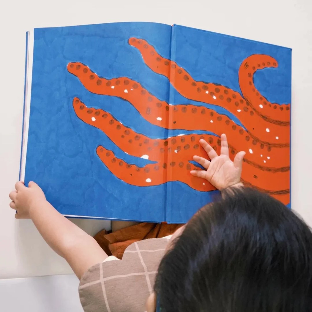 孩子和媽媽一起翻閱繪本《章魚沒有骨頭》，從故事中認識數字與生活。